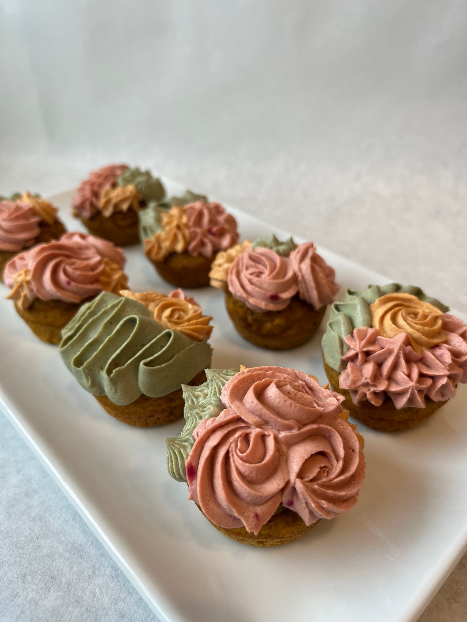 Mini custom dog cupcakes with mixed flower design (pink, green, and yellow icing).