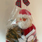 Christmas-themed gift bag with Santa Claus design and plaid bow on a white background