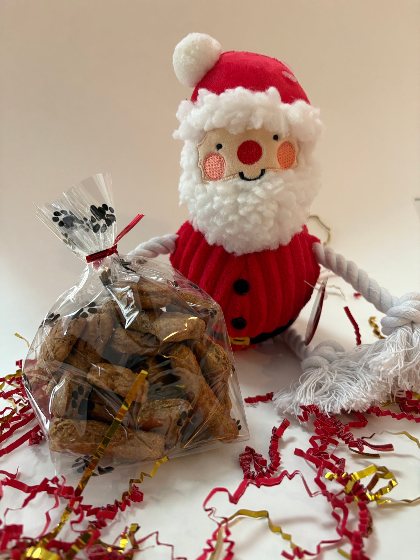 Bag of dog treats with a Santa Claus toy and decorative paper in the background