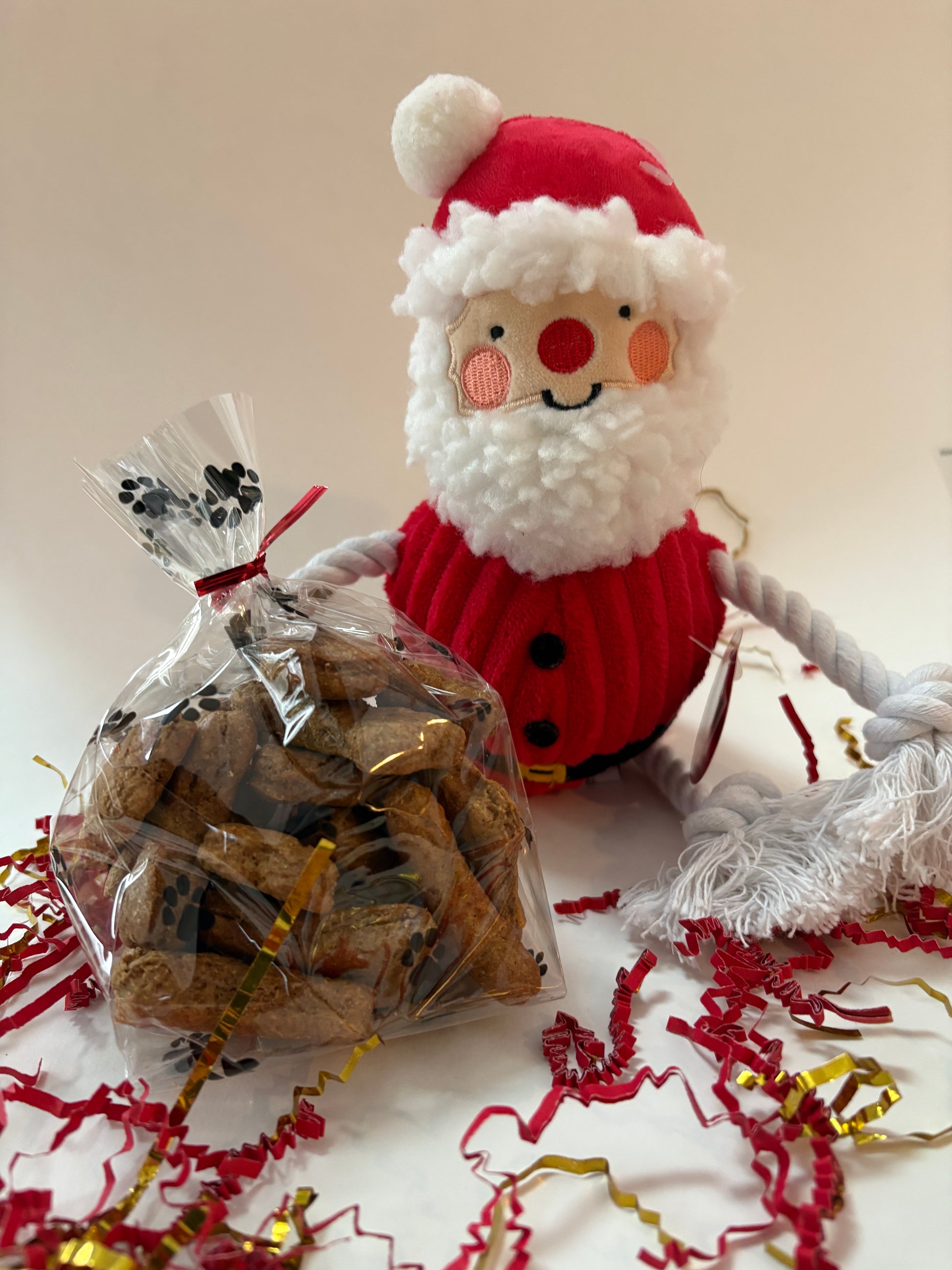 Bag of dog treats with a Santa Claus toy and decorative paper in the background