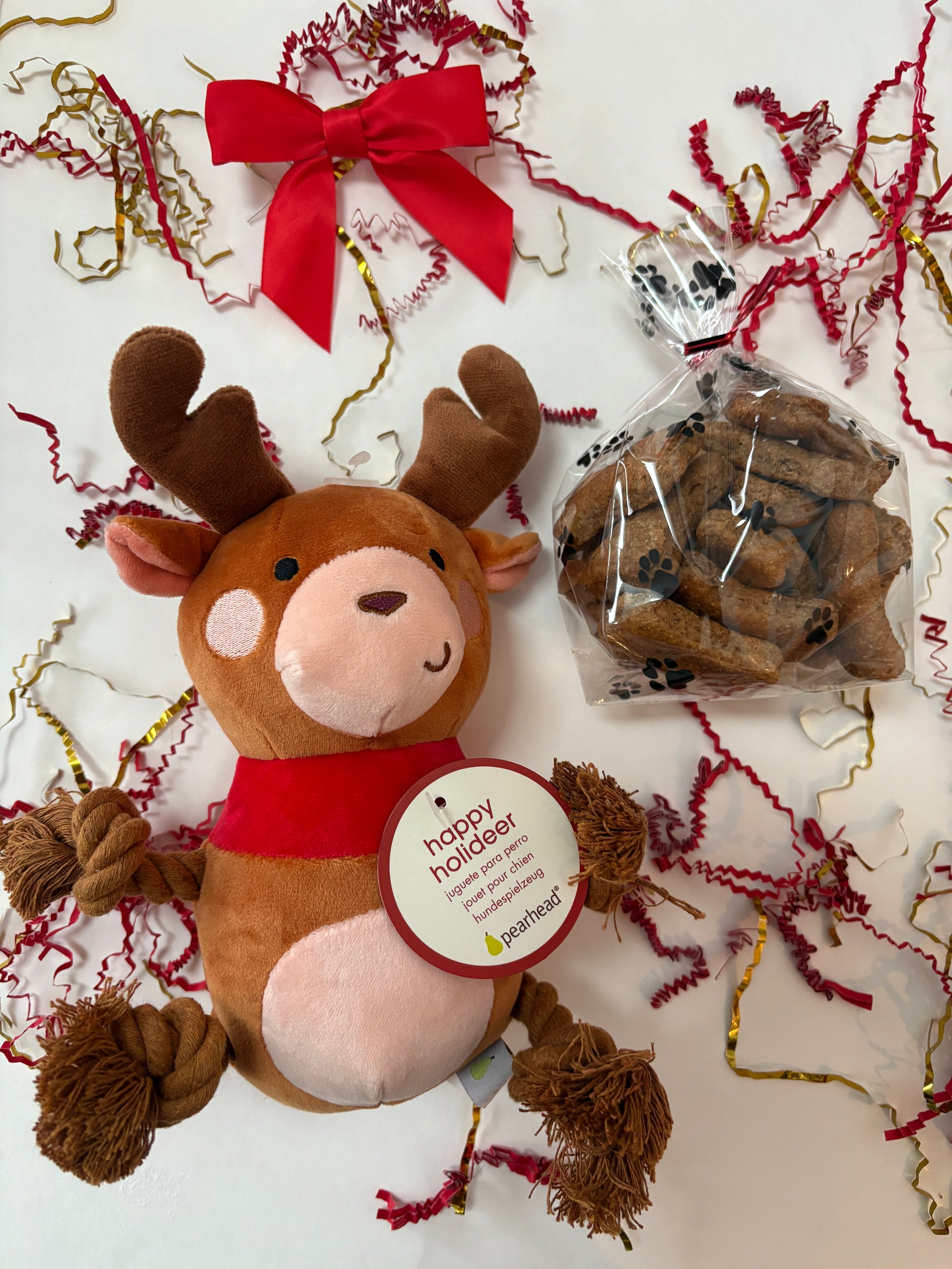 Plush reindeer toy, dog treats, and decorative ribbons on a white background